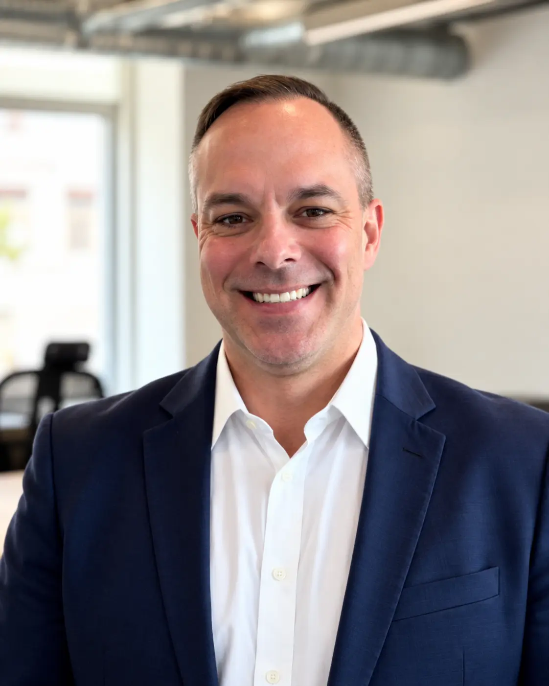 Professional man in navy blazer and white shirt smiling in modern office